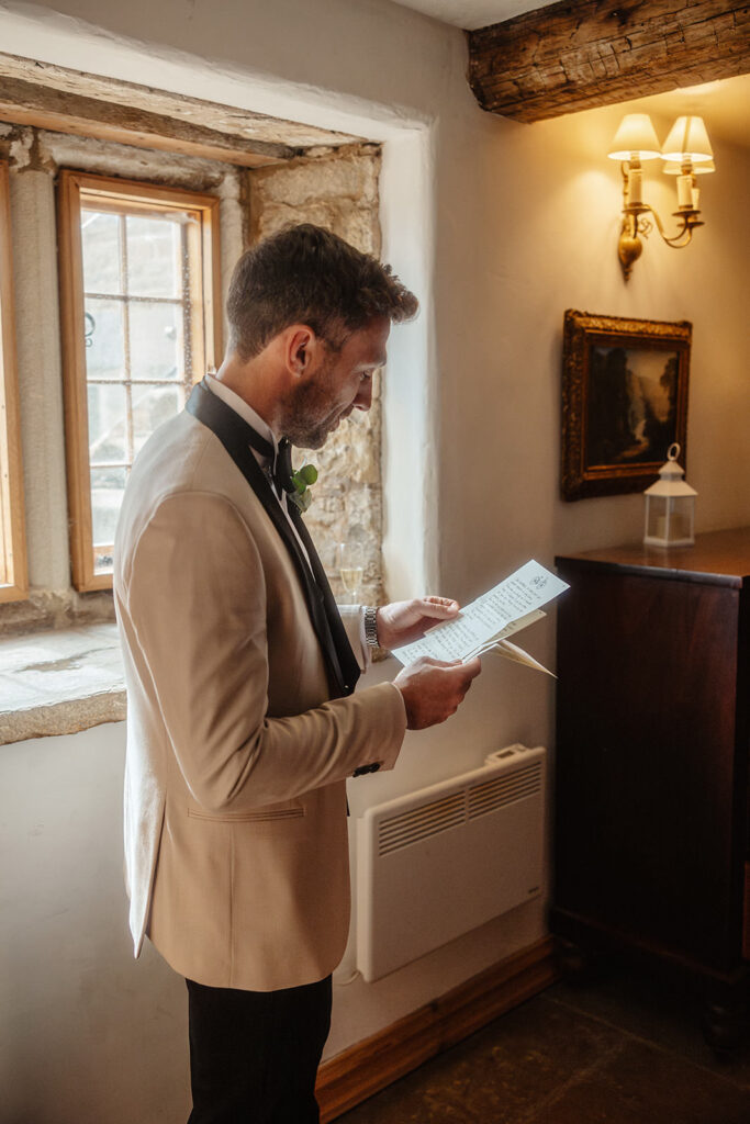 Groom reading love letter before wedding ceremony at Barlow Woodseats Hall