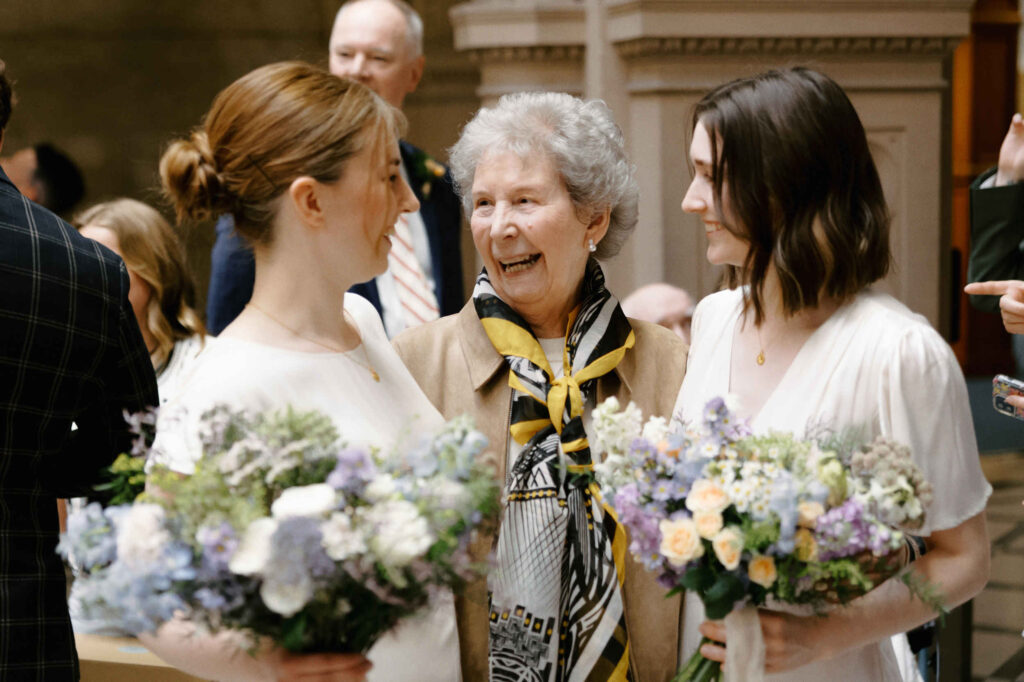 Candid Wedding Photo of same sex couple cuddling their grandmother