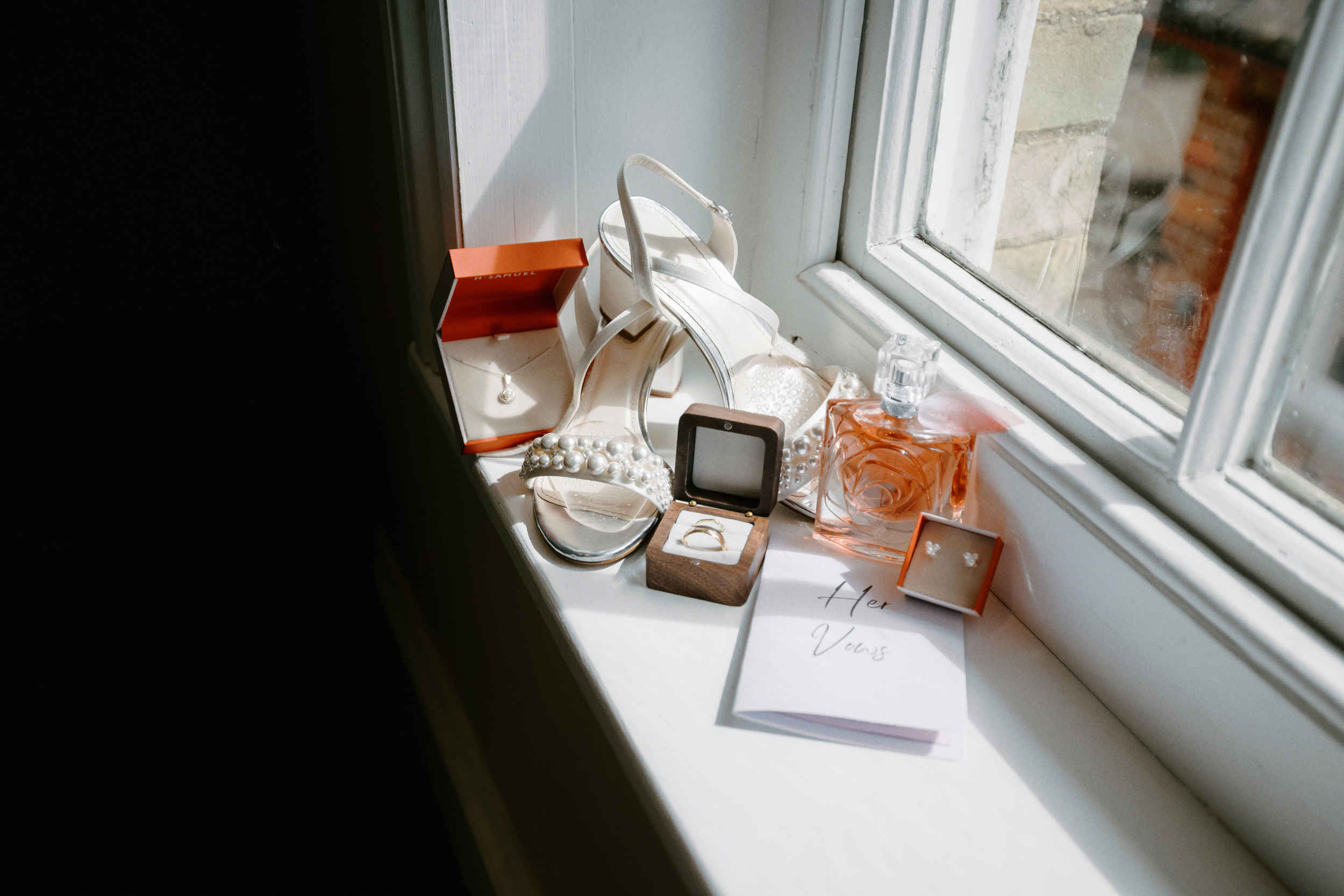 Detail photograph of brides jewellery, perfume and bridal shoes.