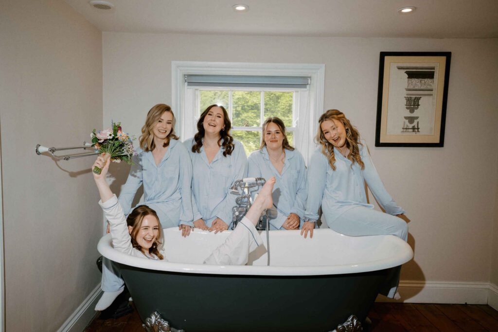 Photograph of bride in the bath with a wedding boquet surrounded by bridesmaids at Sledmere House wedding in Driffield