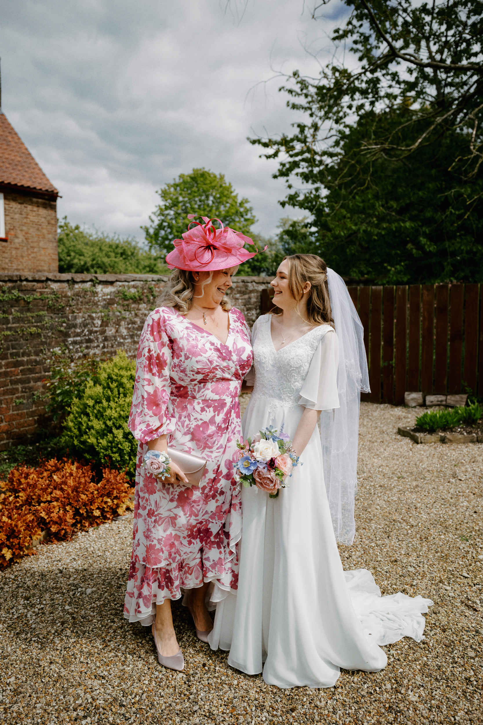 Mother and the bride smiling at each other in the grounds of Sledmere House.
