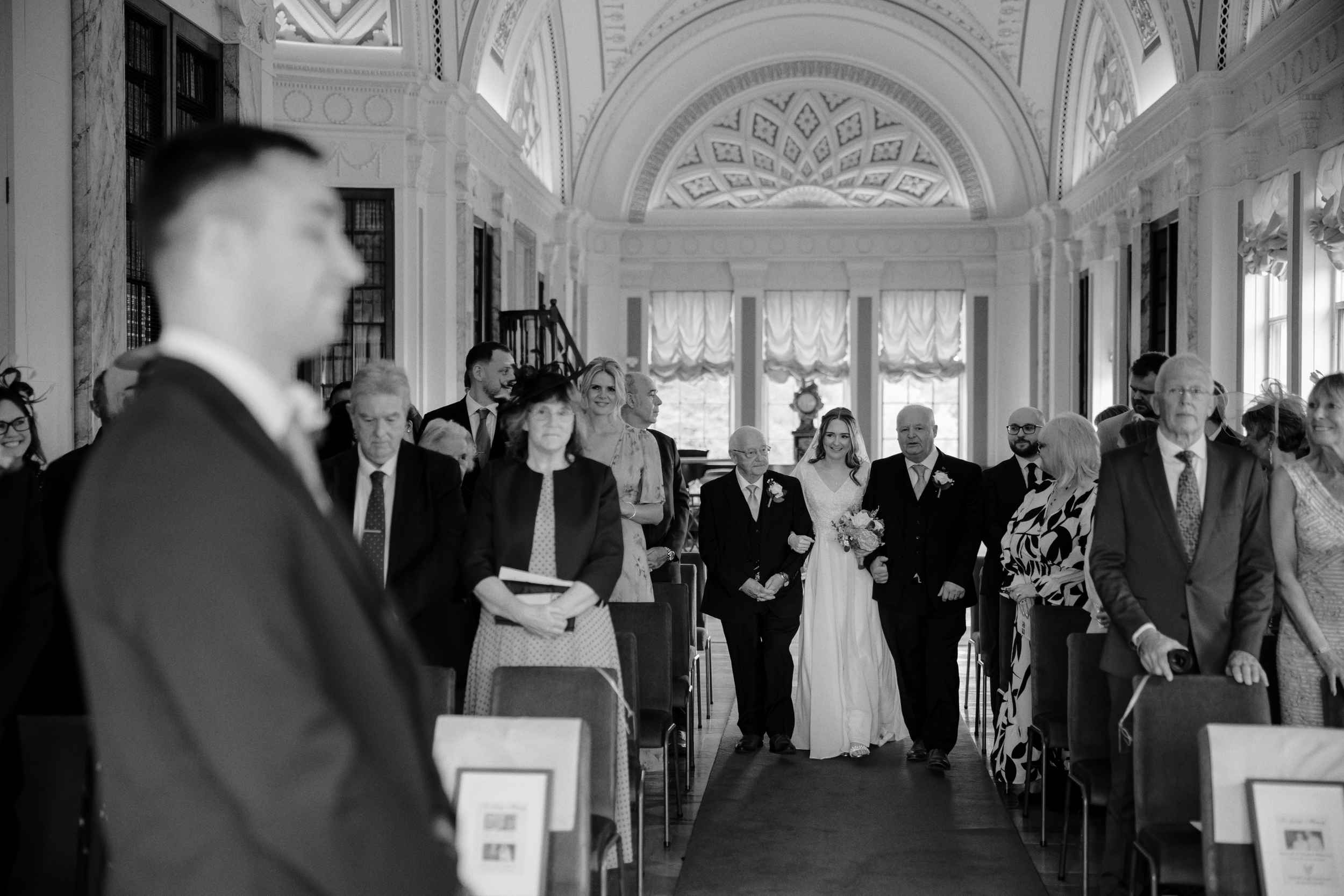 B&W image of the bride being walked down the aisle by father and grandfather at Sledmere House in Driffield.