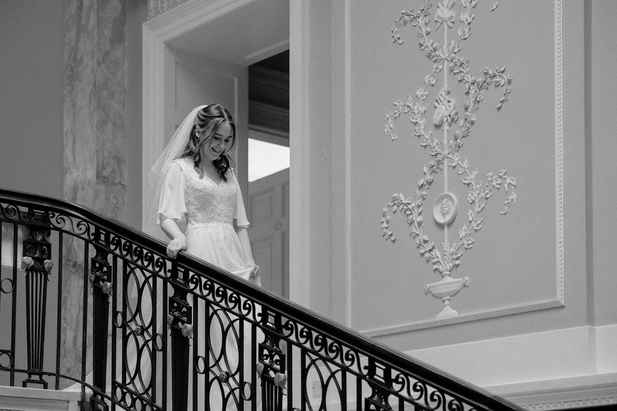 Editorial black and white image of the bride walking down the staircase at Sledmere House