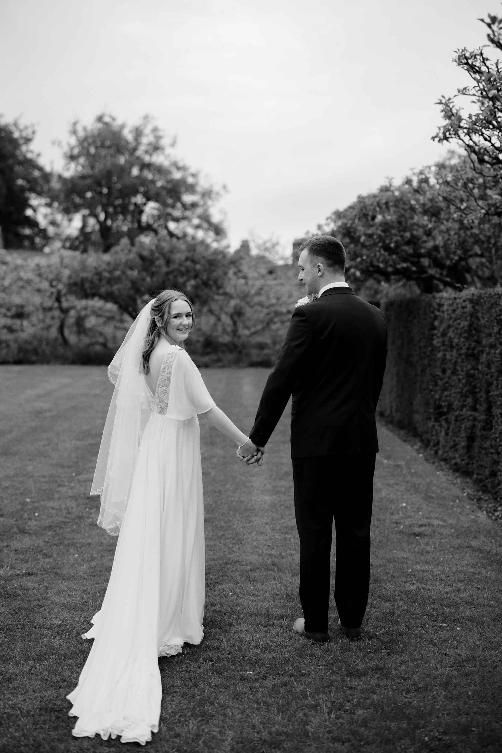Editorial B&W image of the bride looking over her shoulder in the gardens of Sledmere House