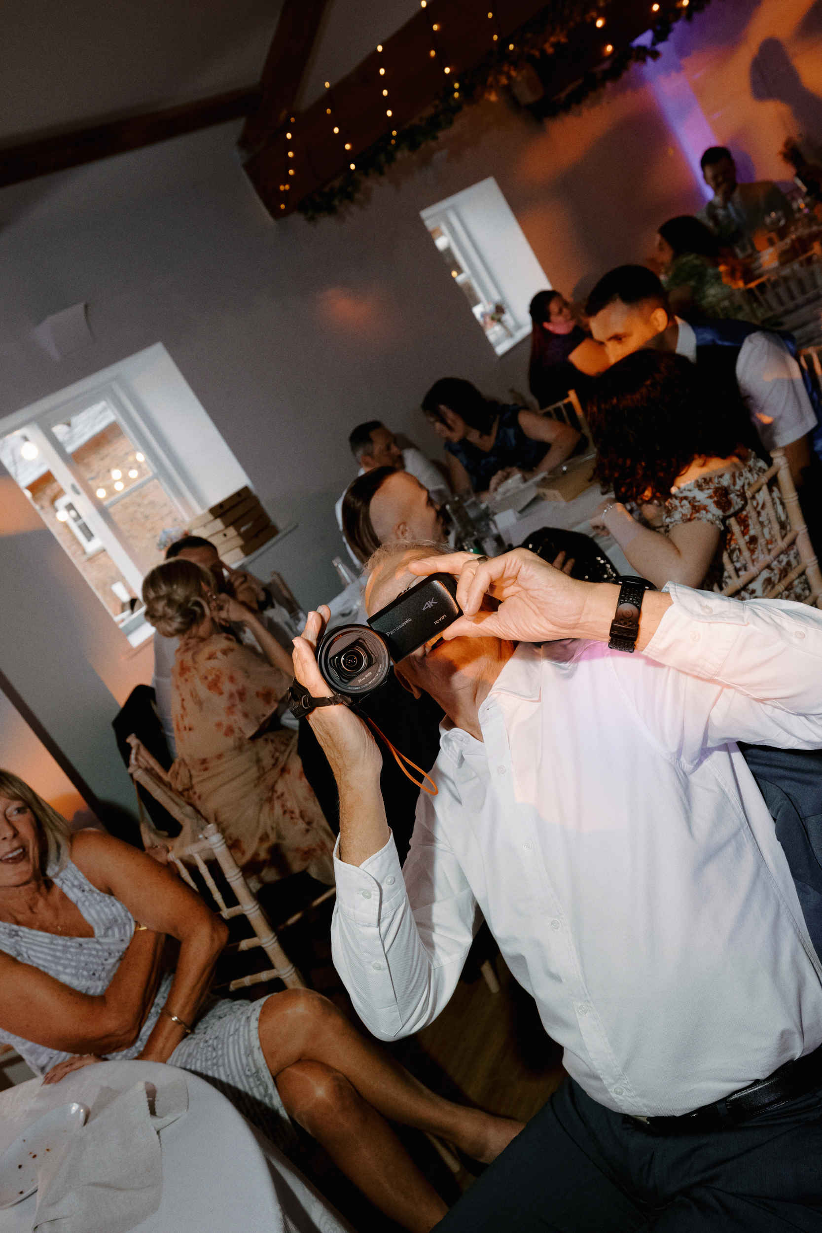Documentary wedding photograph of guest holding a camcorder to the camera at Sledmere House.