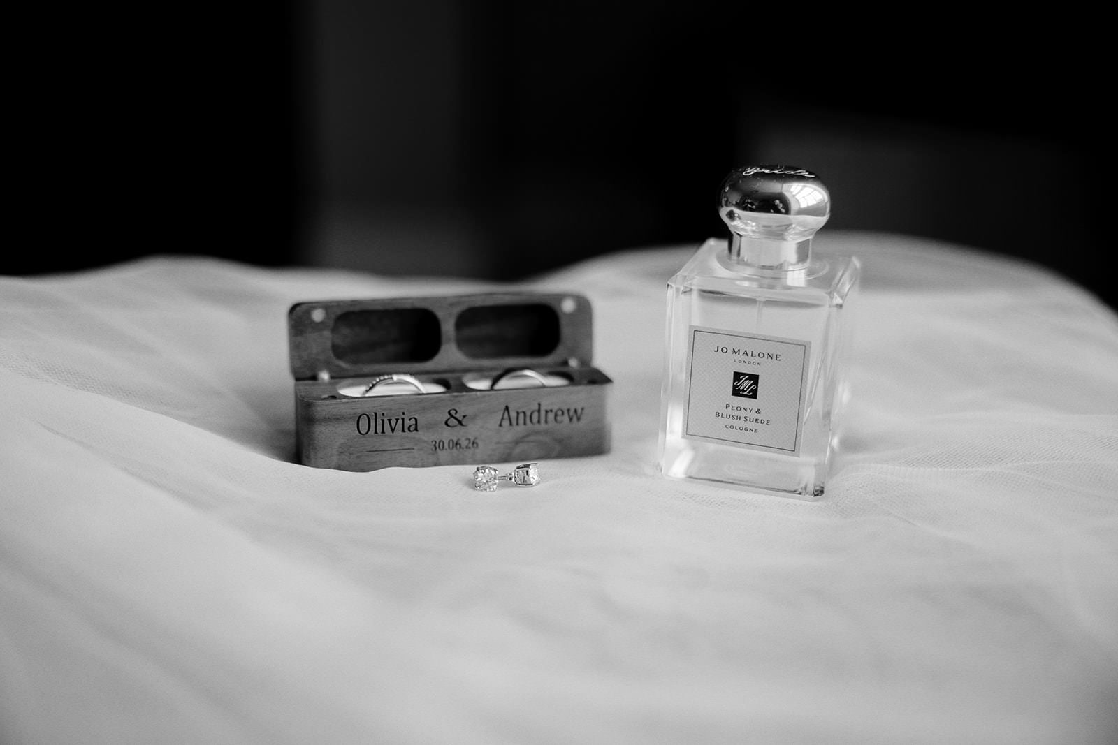 Wooden ring box engraved Olivia and Andrew next to a bottle of Jo Malone cologne