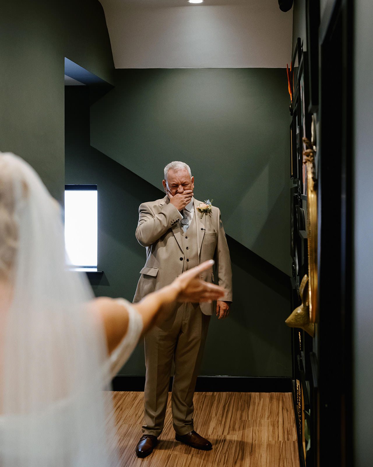 Father of the bride covering his mouth with emotion as he sees his daughter in her wedding dress for the first time