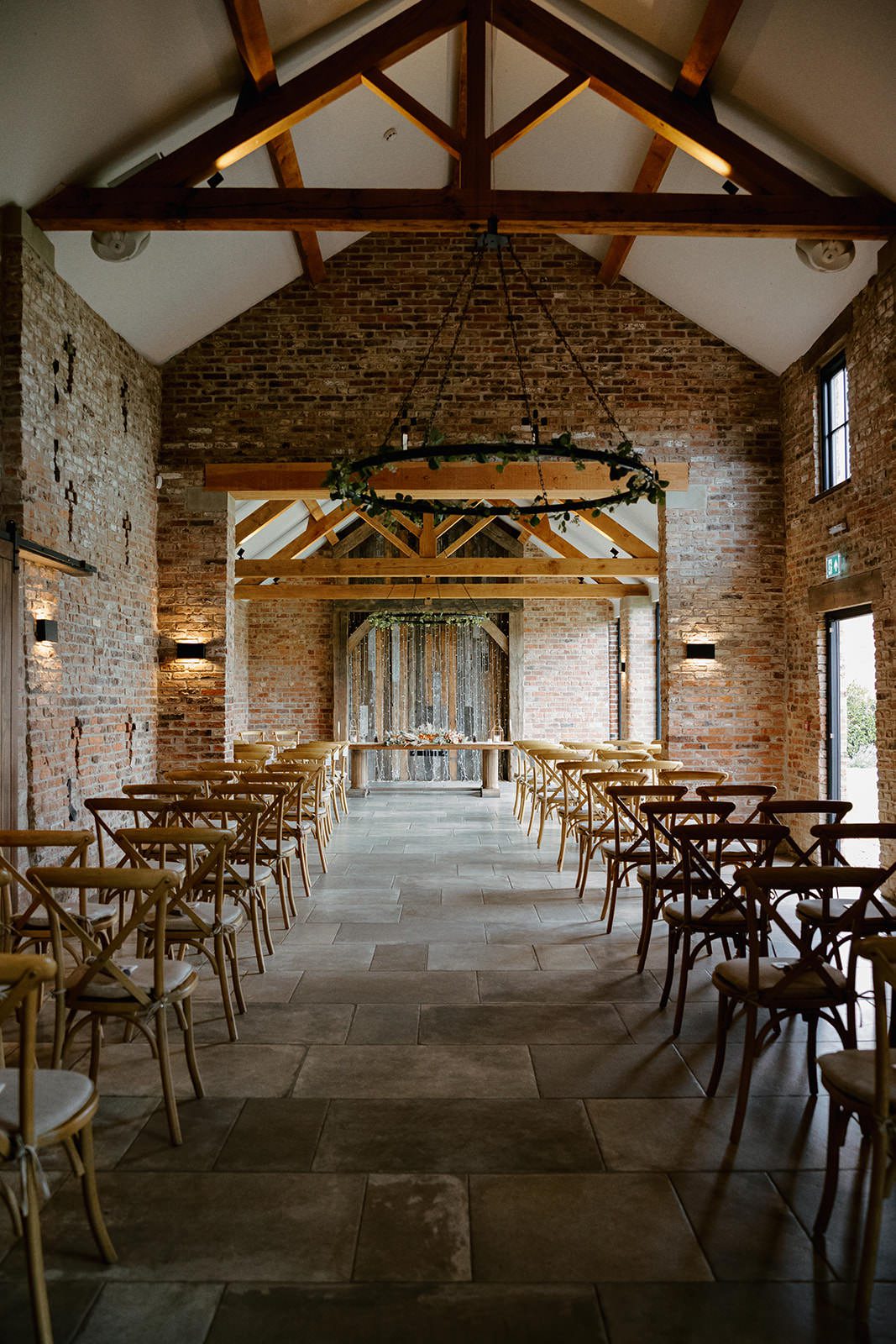 Main Barn ceremony room at Thirsk Lodge Barns with oak beams, flagstone floor and an iron chandelier