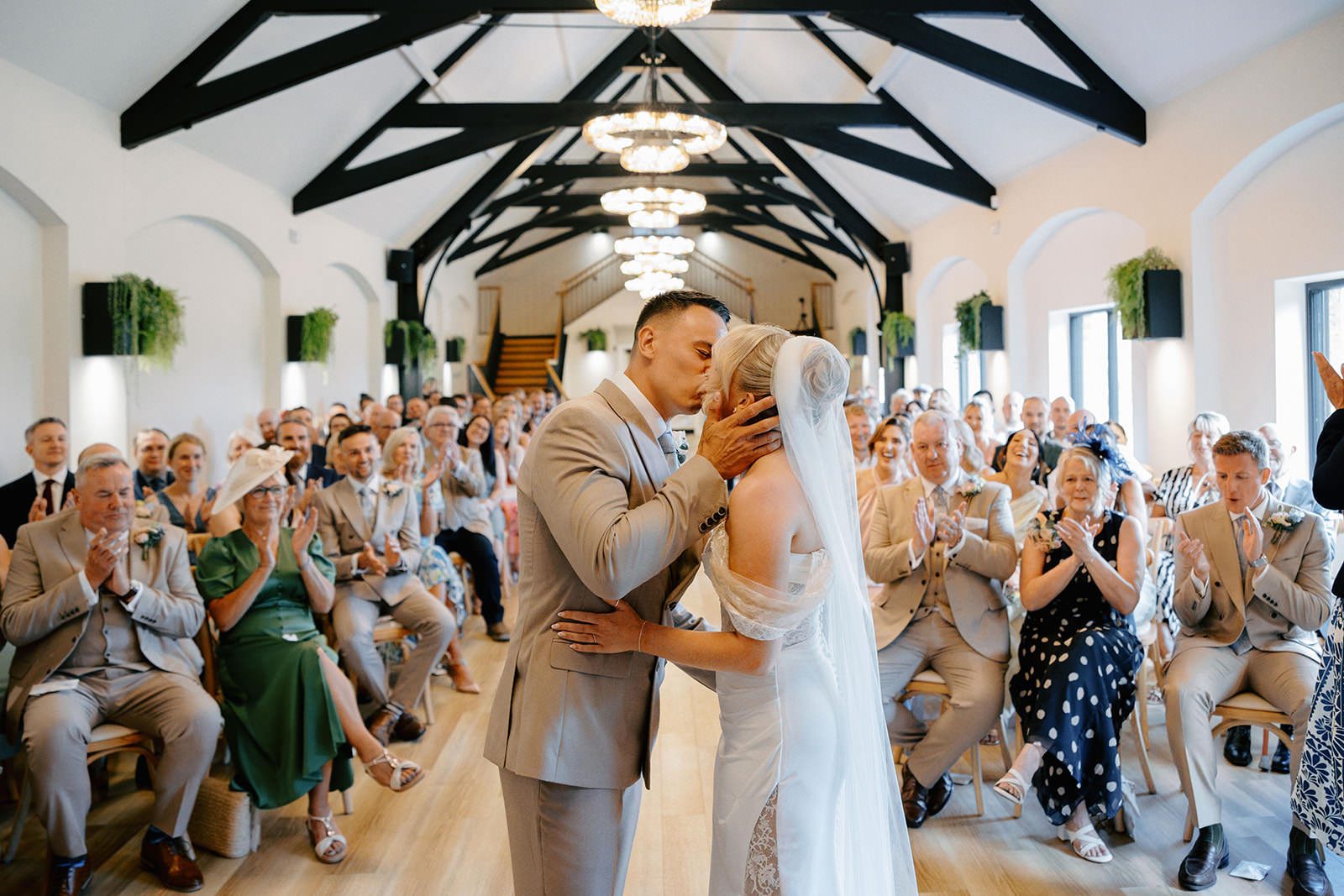 Bride and groom share their first kiss as guests applaud in the Whistle Barns ceremony barn