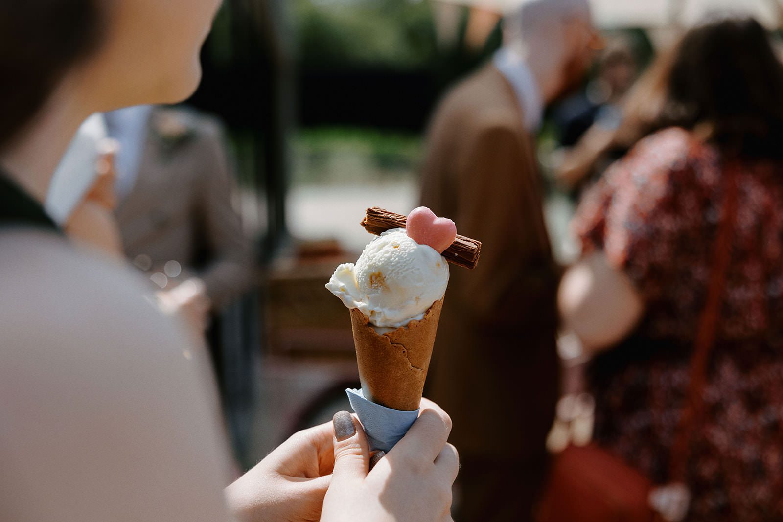 Guest holding an ice cream cone with a Flake and pink heart from the ice cream trike