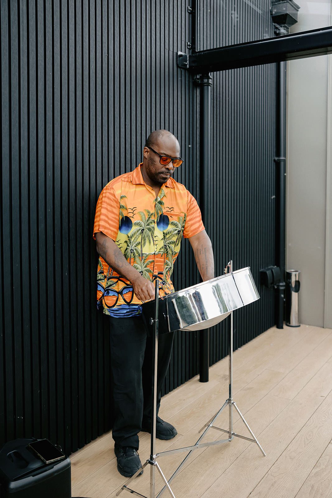 Steel pan drummer in a tropical print shirt playing on the Whistle Barns terrace