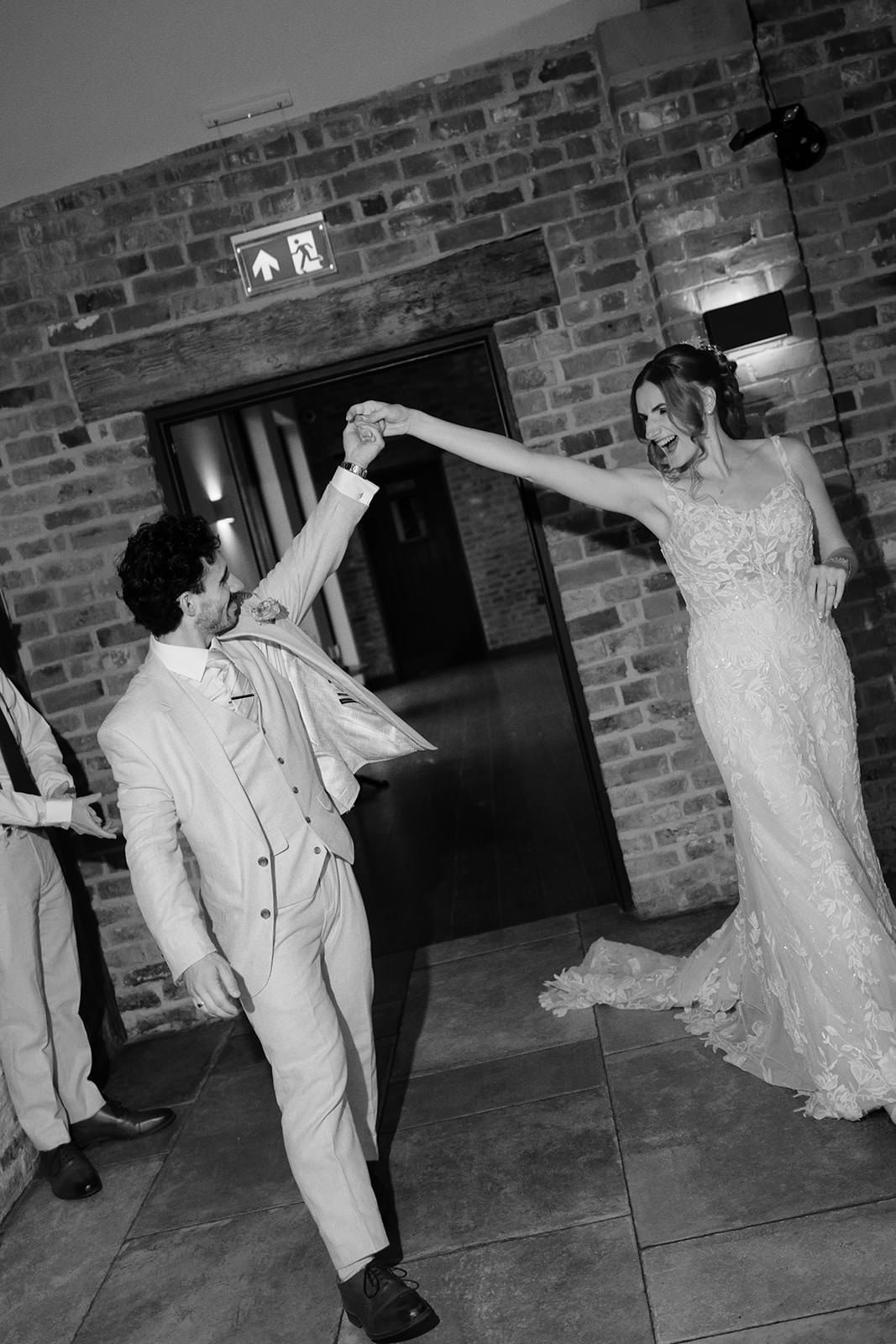 Black and white photo of the groom twirling the bride as they make their entrance