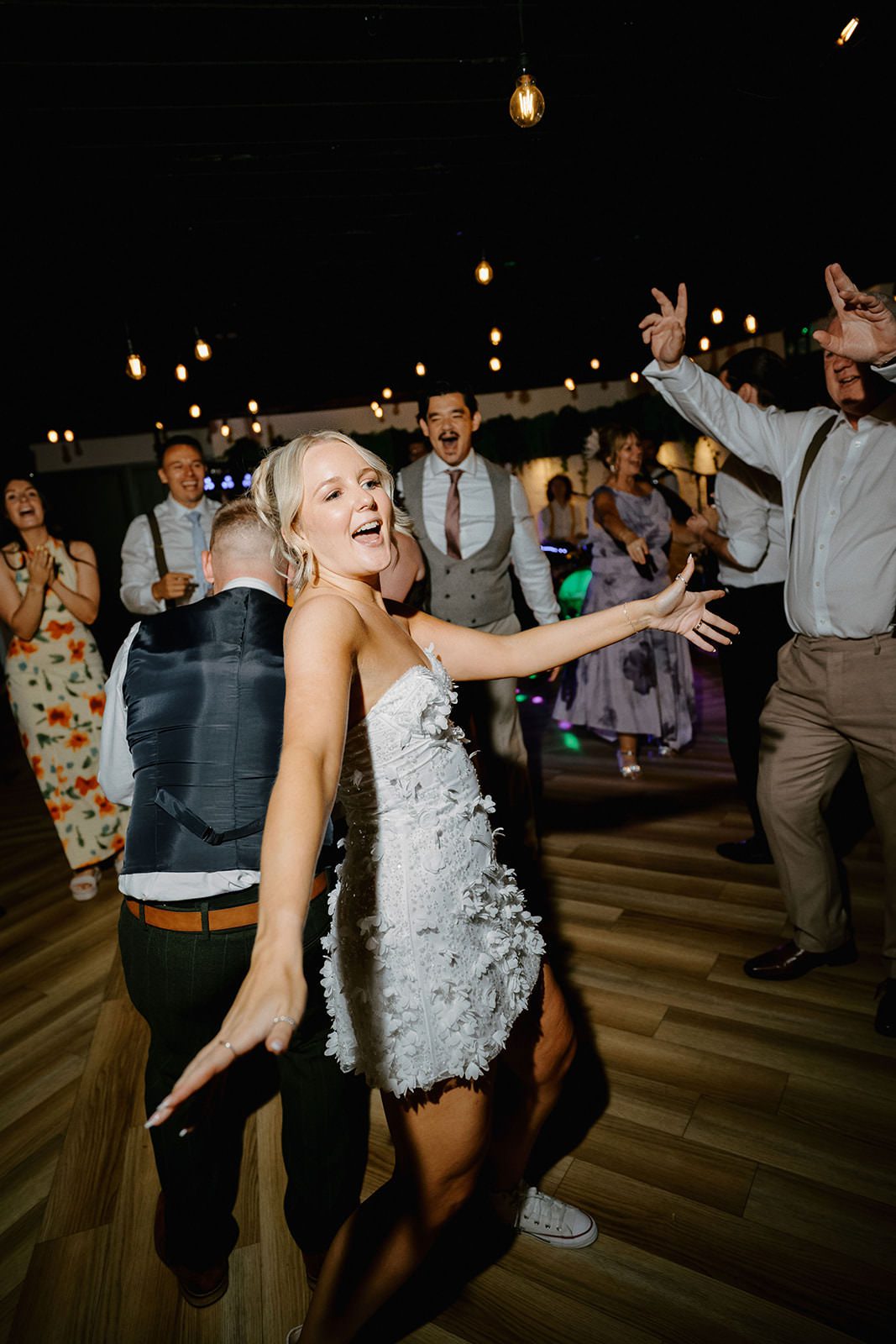 Bride in a short floral party dress singing and dancing with guests in the evening