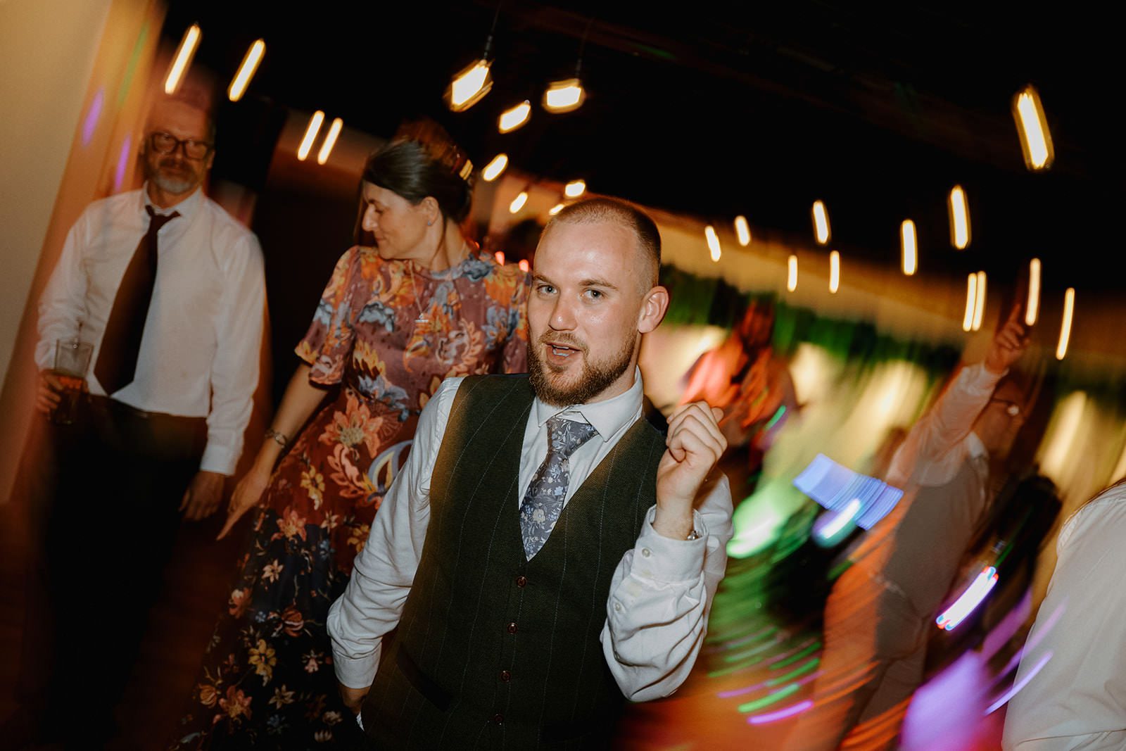 Guest in a waistcoat dancing among blurred coloured disco lights