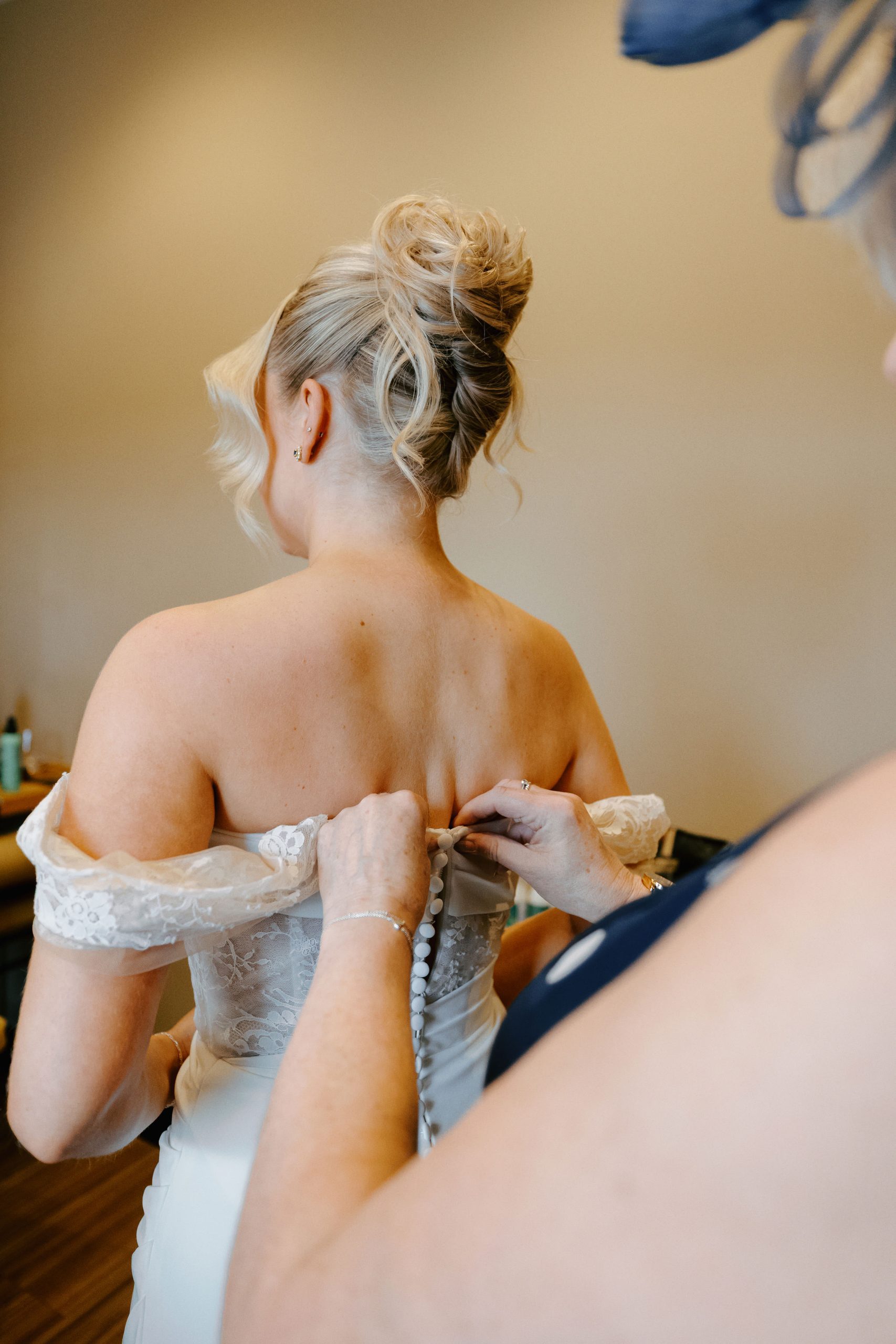 Bride's mum fastening the buttons down the back of the wedding dress in the Whistle Barns dressing room